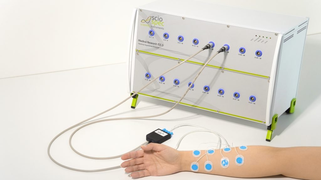 Researcher using the Medical Research ISX-3 impedance analyzer to measure electrodermal activity (EDA) on a subject’s arm in a high-tech laboratory setting.