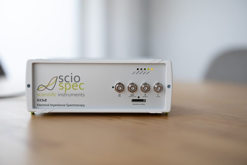 Sciospec ISX-3 Impedance Analyzer device connected to a computer, used for bioimpedance measurements in DNA analysis with magnetic nanoparticles