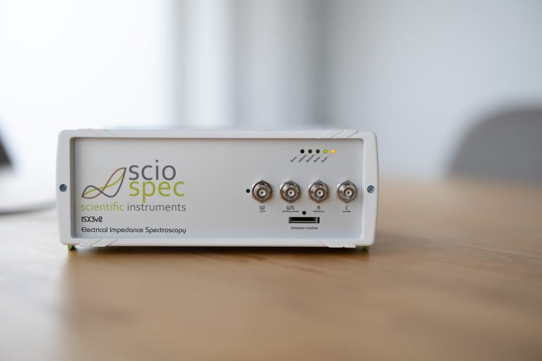 Sciospec ISX-3 Impedance Analyzer device connected to a computer, used for bioimpedance measurements in DNA analysis with magnetic nanoparticles