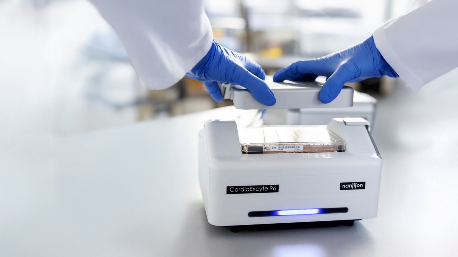 loading a standard 96-well plate into the Sciospec-powered Nanion CardioExcyte 96, demonstrating industrial throughput capabilities.